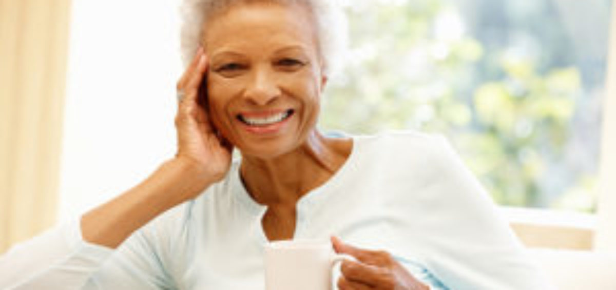 Senior African American woman on couch holding a cup of coffee