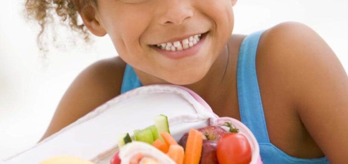 Girl holding lunch box full of healthy foods